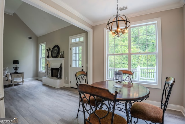 dining area featuring a wealth of natural light, wood-type flooring, lofted ceiling, and ornamental molding