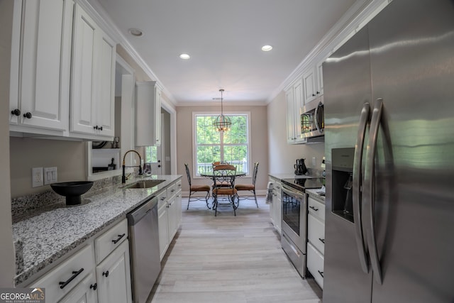 kitchen featuring white cabinets, crown molding, sink, hanging light fixtures, and stainless steel appliances