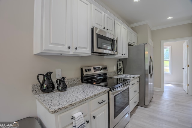 kitchen with appliances with stainless steel finishes, light hardwood / wood-style floors, white cabinetry, and ornamental molding