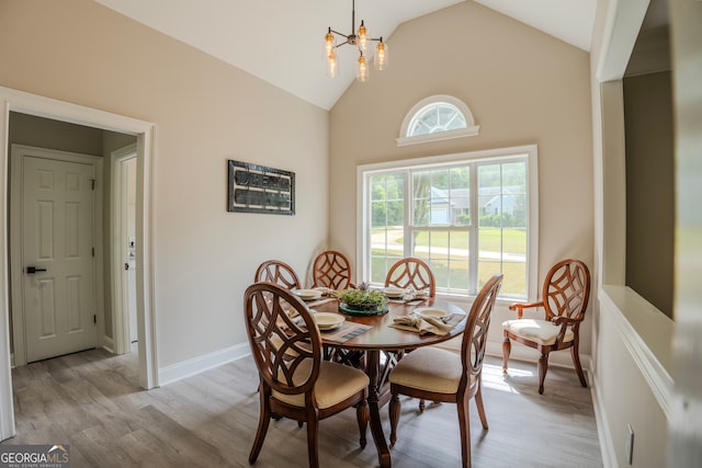 dining space with an inviting chandelier, light hardwood / wood-style floors, and high vaulted ceiling