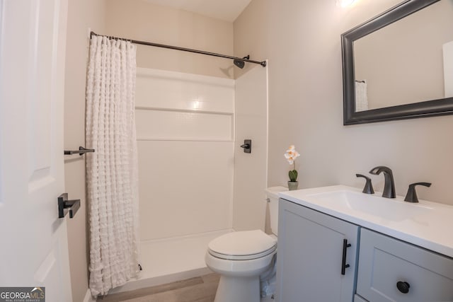 bathroom with wood-type flooring, vanity, toilet, and curtained shower