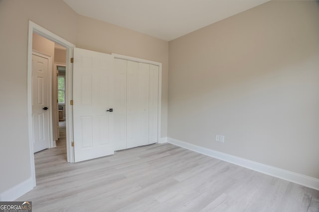 unfurnished bedroom with a closet and light hardwood / wood-style floors