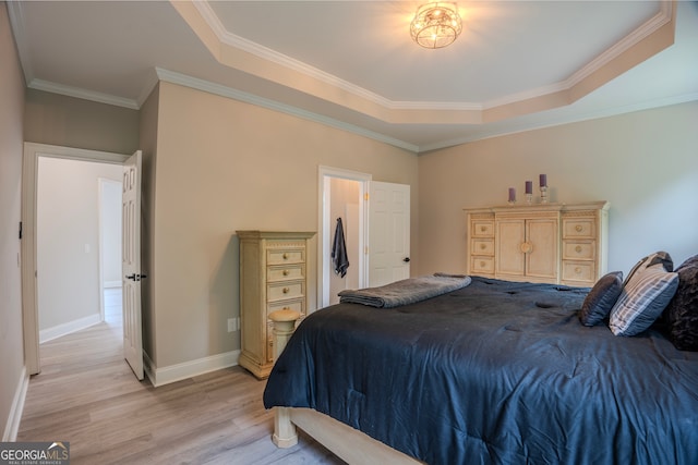 bedroom featuring a raised ceiling, crown molding, and light wood-type flooring