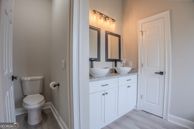 bathroom with wood-type flooring, vanity, and toilet