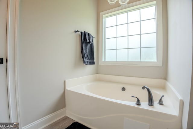 bathroom with hardwood / wood-style flooring, a washtub, and a wealth of natural light