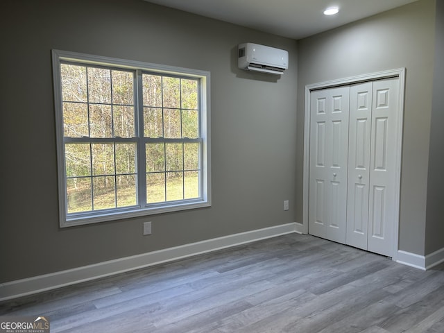 unfurnished bedroom featuring hardwood / wood-style floors, a closet, and a wall mounted AC