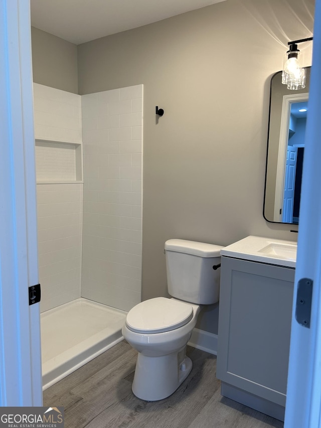 bathroom with hardwood / wood-style flooring, toilet, a shower, and vanity