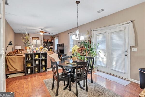 dining room with hardwood / wood-style flooring and ceiling fan with notable chandelier