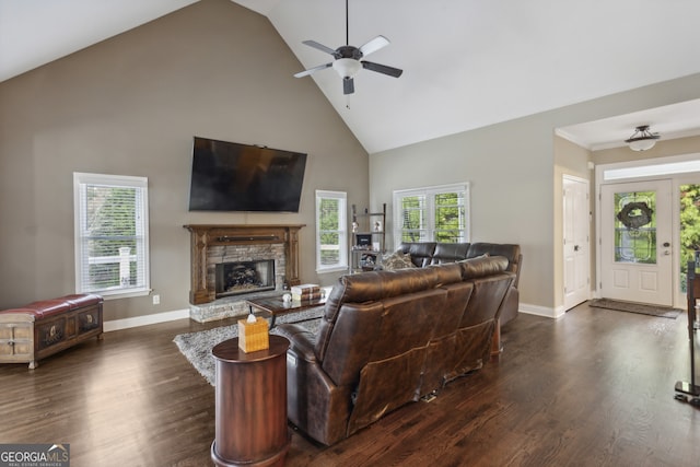 living room with ceiling fan, dark hardwood / wood-style flooring, high vaulted ceiling, and a stone fireplace