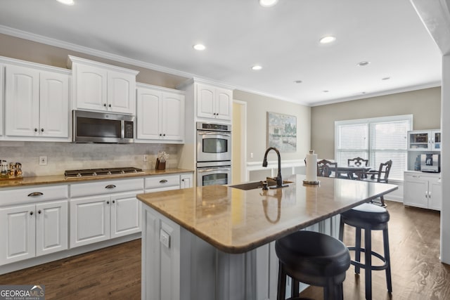 kitchen with white cabinetry, sink, a breakfast bar area, stainless steel appliances, and a center island with sink