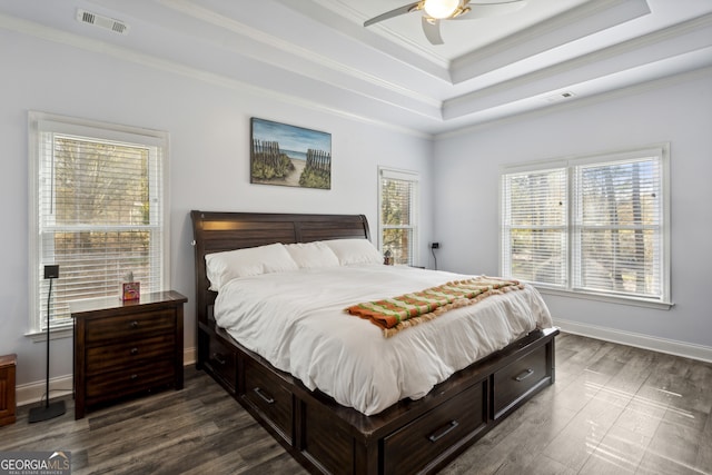 bedroom with ceiling fan, ornamental molding, a tray ceiling, and dark hardwood / wood-style flooring