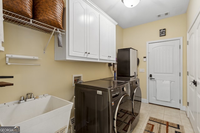 washroom featuring independent washer and dryer, cabinets, sink, and light tile patterned floors