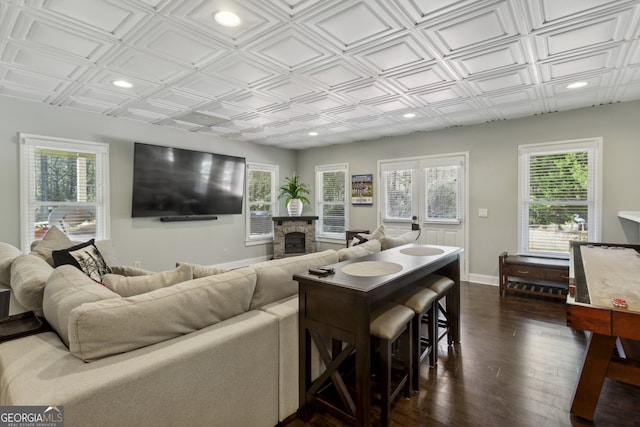 living room with a fireplace, dark wood-type flooring, and a healthy amount of sunlight