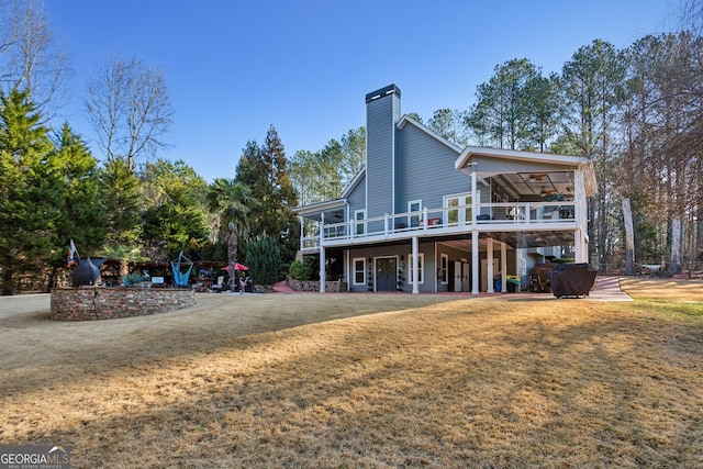 rear view of house featuring a lawn, a sunroom, and a deck