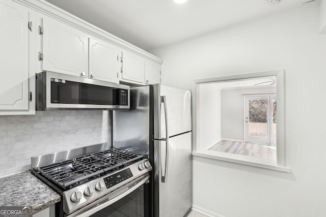 kitchen with baseboards, appliances with stainless steel finishes, white cabinets, and decorative backsplash