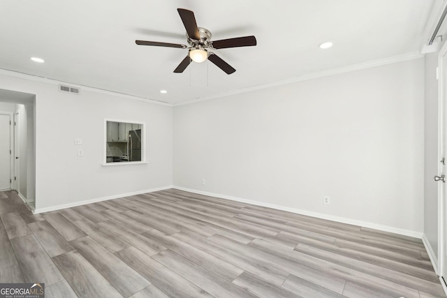 empty room with light wood-style floors, visible vents, crown molding, and baseboards