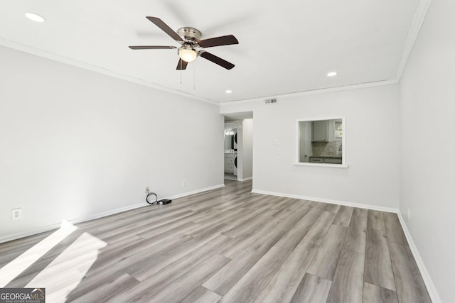 unfurnished room featuring light wood finished floors, baseboards, visible vents, and crown molding