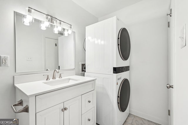 bathroom featuring stacked washer and dryer, baseboards, marble finish floor, and vanity