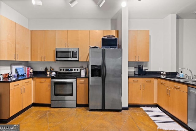 kitchen with appliances with stainless steel finishes, light tile patterned floors, light brown cabinetry, and sink