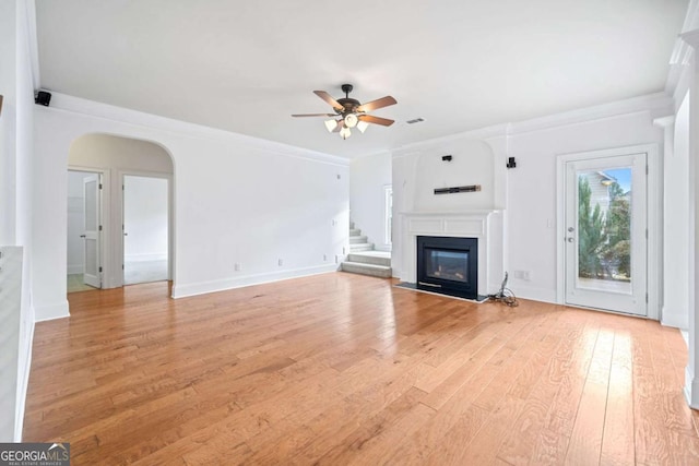 unfurnished living room featuring ceiling fan, light wood-type flooring, and ornamental molding