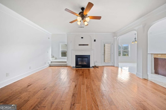 unfurnished living room with ceiling fan, crown molding, and light hardwood / wood-style floors