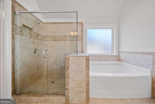 bathroom with tile patterned flooring, separate shower and tub, lofted ceiling, and tile walls