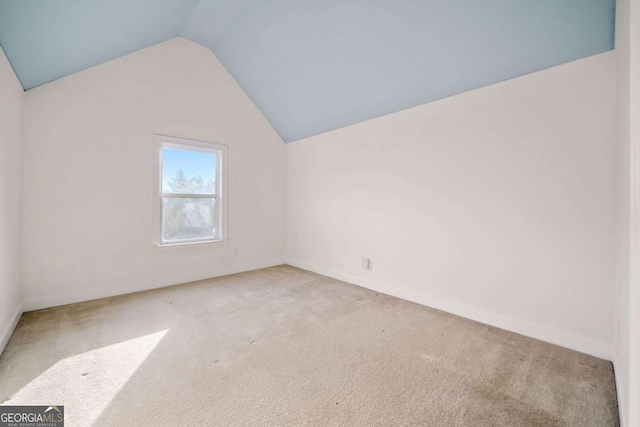 additional living space featuring light colored carpet and vaulted ceiling