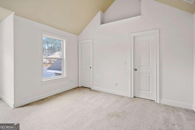 unfurnished room with high vaulted ceiling and light colored carpet