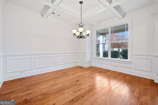 unfurnished dining area featuring beam ceiling, wood-type flooring, coffered ceiling, and an inviting chandelier