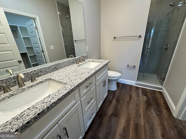 bathroom with hardwood / wood-style floors, vanity, toilet, and a shower with shower door