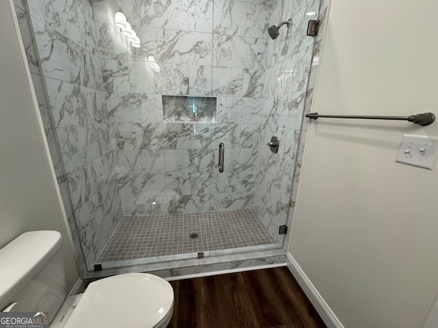 bathroom with hardwood / wood-style flooring, toilet, and a shower with shower door