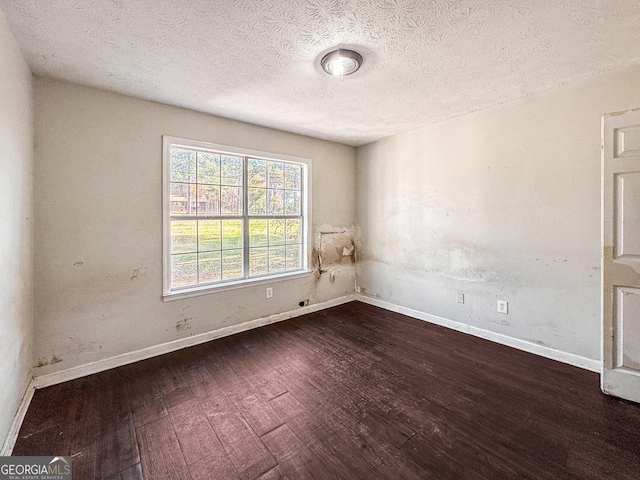 unfurnished room featuring a textured ceiling and dark hardwood / wood-style floors