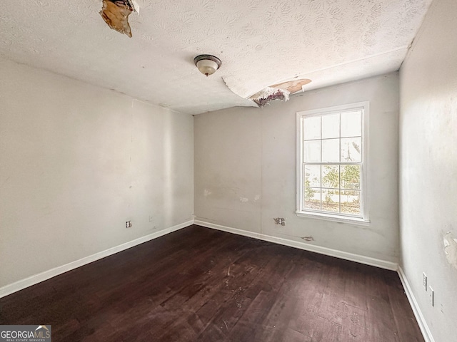 unfurnished room with dark hardwood / wood-style flooring and a textured ceiling