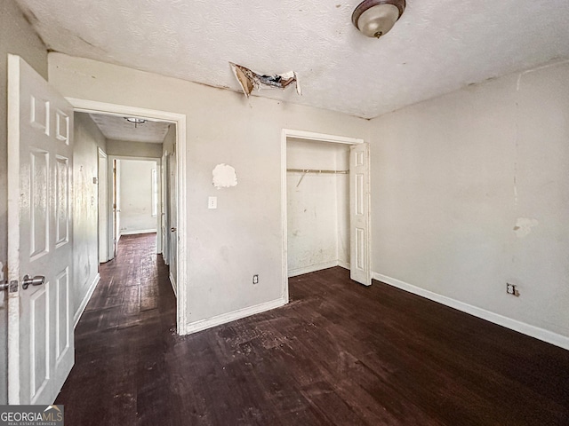 unfurnished bedroom with a closet, dark wood-type flooring, and a textured ceiling