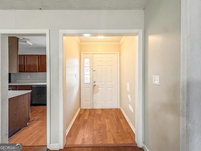 foyer featuring a textured ceiling, light wood-type flooring, and ornamental molding