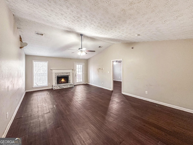 unfurnished living room with a textured ceiling, ceiling fan, a fireplace, dark hardwood / wood-style floors, and lofted ceiling