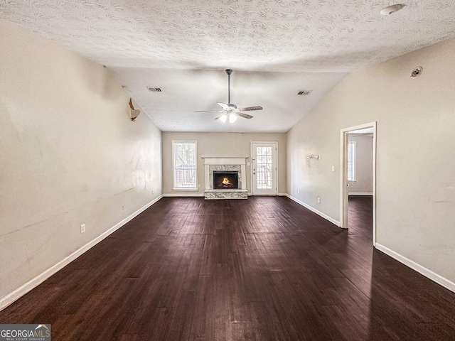 unfurnished living room with a textured ceiling, dark hardwood / wood-style flooring, a high end fireplace, and lofted ceiling