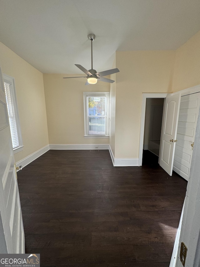 empty room with ceiling fan and dark wood-type flooring