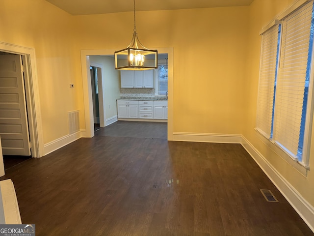 unfurnished dining area featuring dark hardwood / wood-style flooring and a chandelier