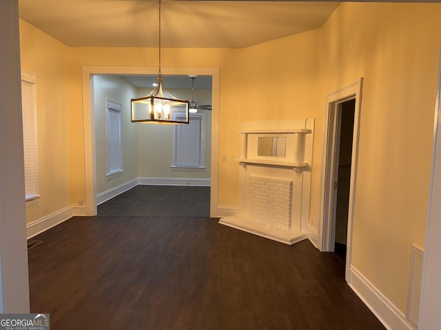 unfurnished dining area featuring dark wood-type flooring and an inviting chandelier