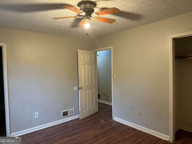 unfurnished bedroom with a textured ceiling, ceiling fan, a closet, and dark hardwood / wood-style floors