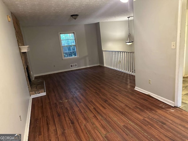 unfurnished living room featuring dark wood-type flooring and a textured ceiling