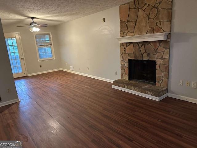 unfurnished living room with a fireplace, ceiling fan, dark hardwood / wood-style flooring, and a textured ceiling