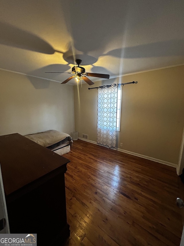 unfurnished bedroom with ornamental molding, dark wood-type flooring, and ceiling fan