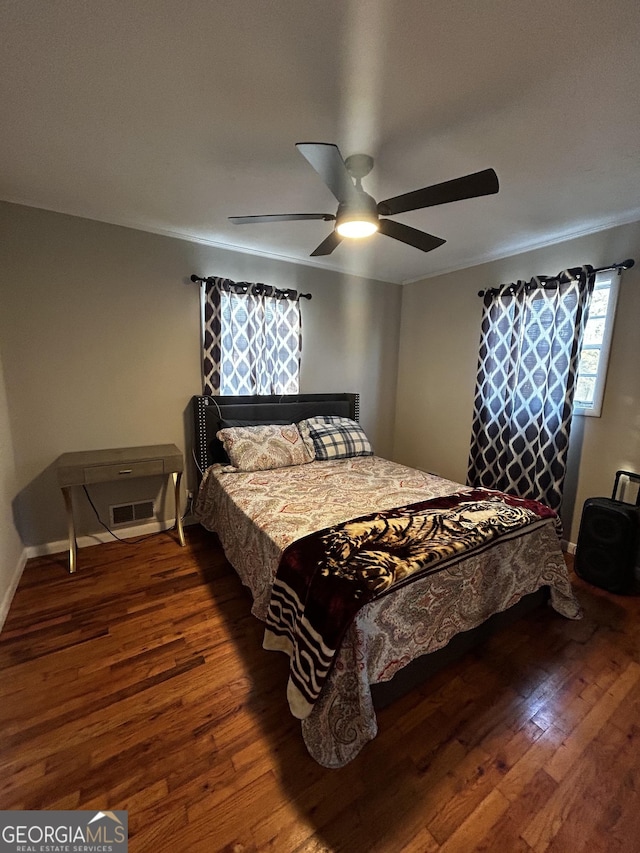 bedroom with dark hardwood / wood-style flooring, ornamental molding, and ceiling fan