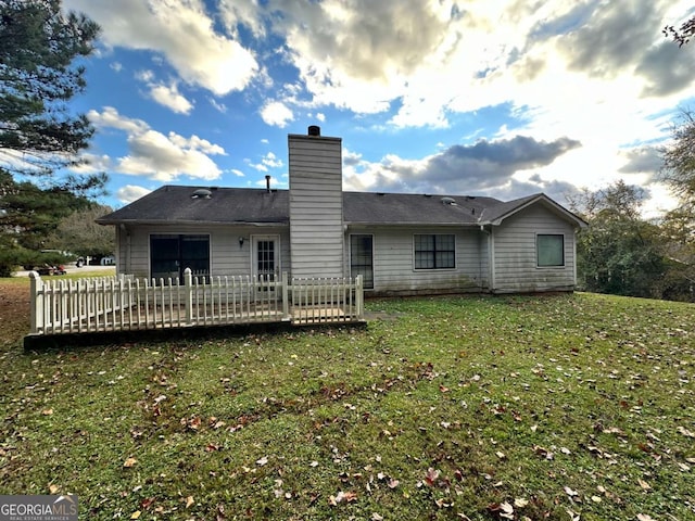 rear view of house featuring a deck and a lawn