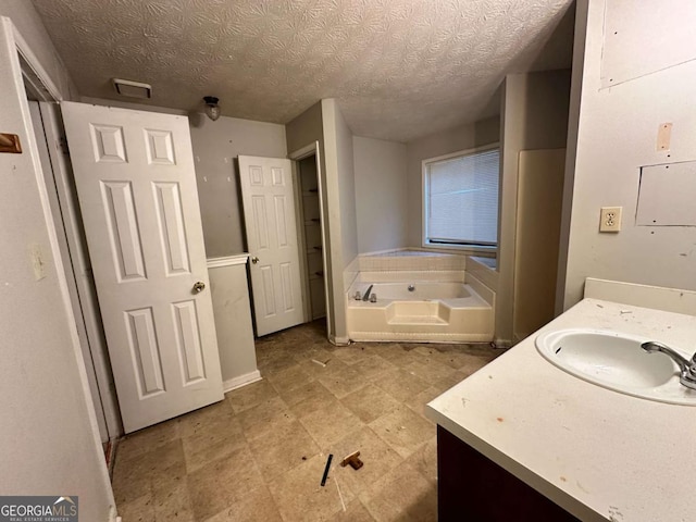 bathroom featuring vanity, a textured ceiling, and a tub