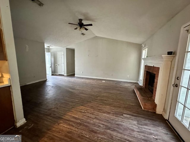 unfurnished living room featuring a brick fireplace, dark hardwood / wood-style floors, ceiling fan, and vaulted ceiling