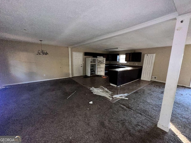 unfurnished living room with dark colored carpet, a textured ceiling, and a chandelier