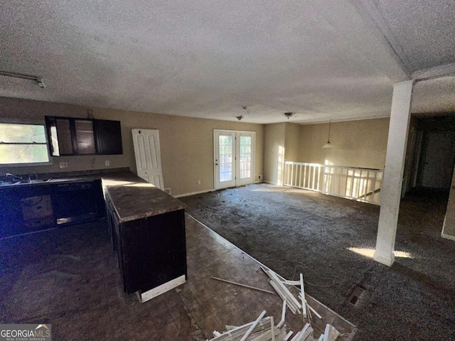 kitchen with french doors, a textured ceiling, sink, dark colored carpet, and a kitchen island